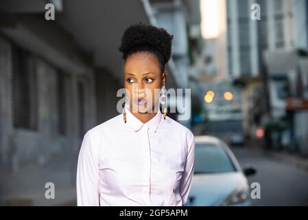charmante jeune femme africaine debout dehors regardant de côté. Banque D'Images