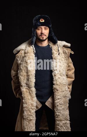 Portrait d'un homme confiant d'aspect caucasien dans un Chapeau de fourrure d'officier soviétique et manteau de peau de mouton de l'armée Banque D'Images