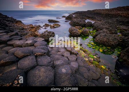 Coucher de soleil sur la formation des roches basaltiques Giant's Causeway, Port Ganny Bay et Great Stookan, comté d'Antrim, en Irlande du Nord, Royaume-Uni Banque D'Images