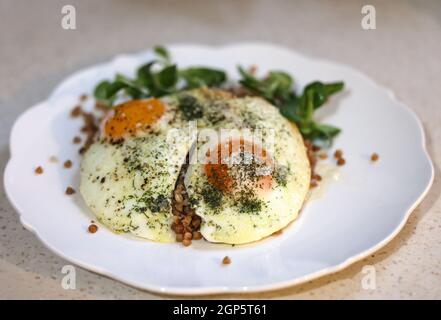 Œuf frit avec sarrasin et arugula sur une assiette blanche Banque D'Images