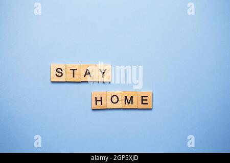 Lettres décoratives en bois formant le mot rester à la maison sur un fond blanc, vue de dessus Banque D'Images