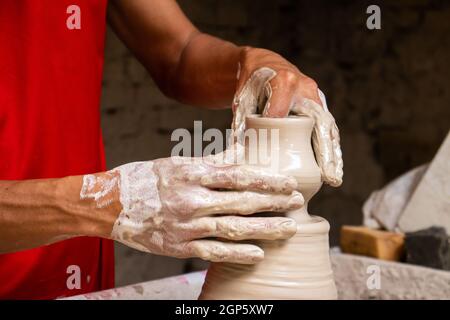 Homme faisant des articles en céramique sur la roue de potiers dans un Usine traditionnelle dans la ville de Ráquira située dans le département de Cundinamarca en Colombie Banque D'Images