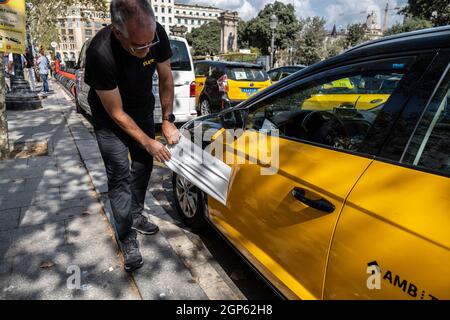 Barcelone, Espagne. 28 septembre 2021. Un chauffeur de taxi a vu déchirer le logo de FreeNow de son véhicule de taxi devant le siège de Free Now Barcelona sur la Plaza Catalunya.les chauffeurs de taxi ont participé à une marche lente contre les compagnies de transport avec des conducteurs Uber et Free Now, Qu'ils accusent de concurrence déloyale selon les règlements de l'Institut métropolitain de taxi. Crédit : SOPA Images Limited/Alamy Live News Banque D'Images