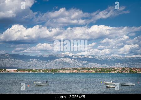Bateaux à moteur et pontons ancrés près de la plage de Zdrijac entre la baie de Nin Et la mer Adriatique avec la chaîne de montagnes des Alpes Dinaric dans l'arrière-plan Banque D'Images