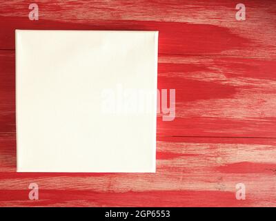 Concept d'invitation avec une toile vierge sur fond en bois rouge, invitation, carte de voeux, créativité à la maison Banque D'Images