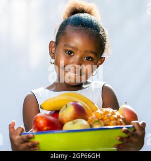 Gros plan portrait d'une jolie fille africaine tenant un bol de fruits.isolé contre un arrière-plan clair. Banque D'Images