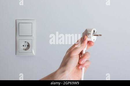 Fiche blanche avec câble dans les hommes de main, prêt à se connecter. Concept de l'énergie. Banque D'Images