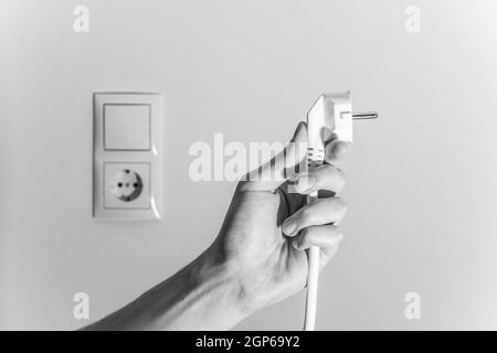 Fiche blanche avec câble dans les hommes de main, prêt à se connecter. Concept de l'énergie. Banque D'Images