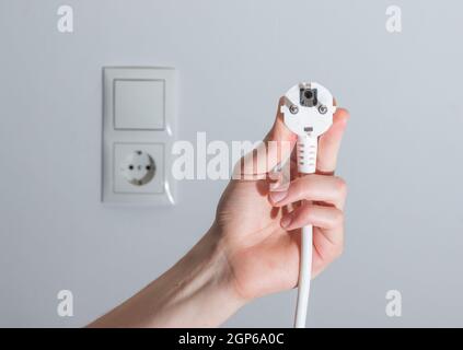 Fiche blanche avec câble dans les hommes de main, prêt à se connecter. Concept de l'énergie. Banque D'Images