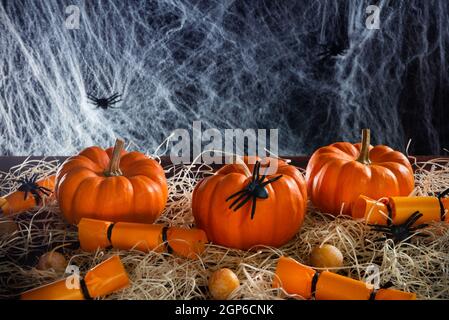 Citrouilles, bonbons, araignées et toile d'araignée décorée de paille sur fond noir, concept de fête d'Halloween, espace de copie Banque D'Images