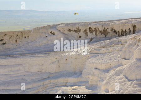 Deux personnes sur un parapente double survolent les travertins de Pamukkale (piscines thermales en cascade) près de l'ancienne ville grecque de Hiérapolis en Turquie. Banque D'Images