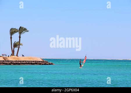 Homme solitaire à bord de planche à voile conduisant sur la mer Rouge pendant la quarantaine du coronavirus. Vacances d'été. Sports nautiques en vacances d'été. Paysage avec Banque D'Images