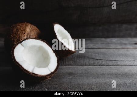 Noix de coco cassées sur fond en bois gris. Pâte de coco blanche. Photo de haute qualité Banque D'Images