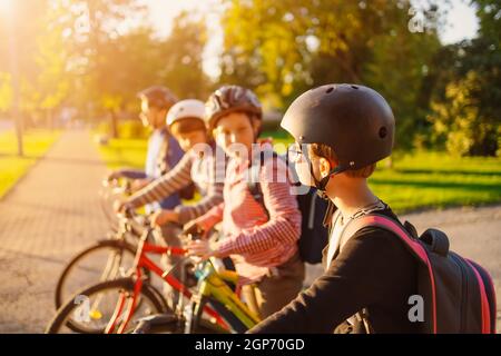 Enfants avec sacs à dos à vélo dans le parc près de l'école. Étudiants avec des sacs à dos à l'extérieur Banque D'Images