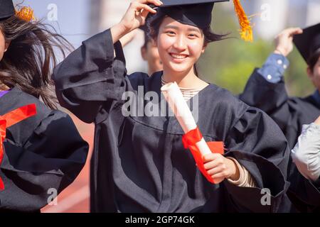 belle fille étudiante asiatique menant un diplôme et s'exécutant sur le stade à l'école Banque D'Images