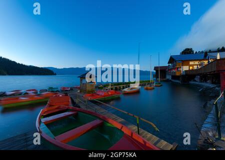 Location de bateaux à rames sur la jetée au lac de montagne Walchensee en Bavière, Allemagne à l'aube en début de matinée avec la maison de bateau Banque D'Images