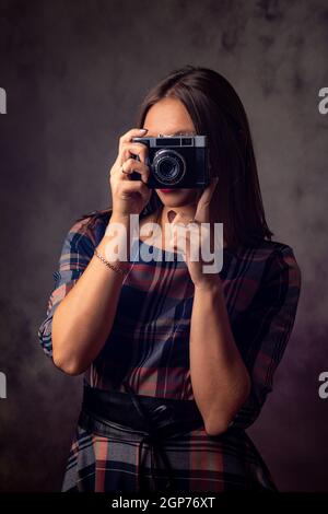 Photographe de fille prend des photos avec un ancien appareil photo, photographie de studio sur un fond gris Banque D'Images