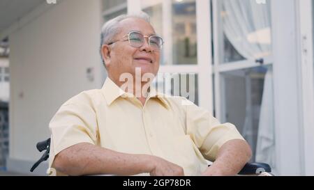 Homme âgé handicapé assis sur un fauteuil roulant seul dans un centre de réadaptation, Portrait Happy Asian génération dehors arrière-cour à la maison, visage de près smil Banque D'Images