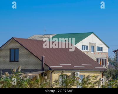 Maisons aux toits en tôle ondulée. Brown et toit vert. Des matériaux modernes pour les toitures Banque D'Images