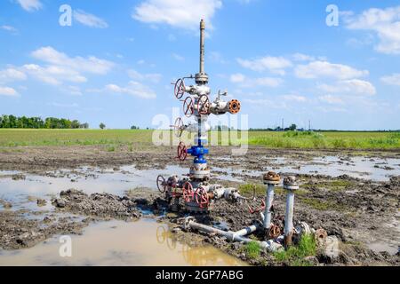 Après la réparation de puits de pétrole dans la boue et les flaques. L'équipement de puits de pétrole. Avec valve d'arrêt pour l'ouverture et la fermeture de la ligne d'écoulement Banque D'Images