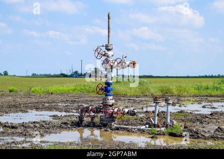 Après la réparation de puits de pétrole dans la boue et les flaques. L'équipement de puits de pétrole. Avec valve d'arrêt pour l'ouverture et la fermeture de la ligne d'écoulement Banque D'Images