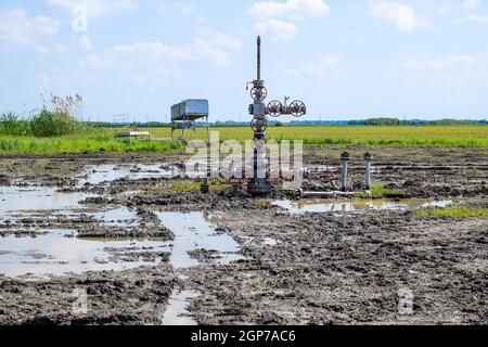 Après la réparation de puits de pétrole dans la boue et les flaques. L'équipement de puits de pétrole. Avec valve d'arrêt pour l'ouverture et la fermeture de la ligne d'écoulement Banque D'Images