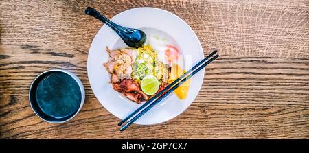 La Soupe miso avec des nouilles asiatiques avec l'oeuf dans un bol sur fond de table en bois avec des baguettes et cuillère Banque D'Images