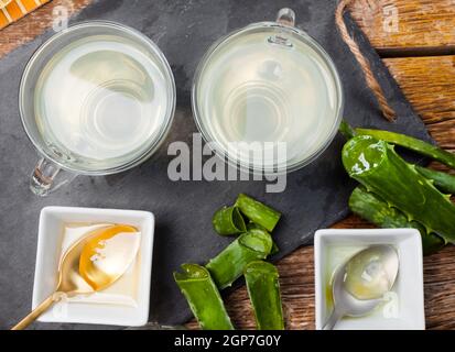 Boire de l'aloe vera et miel. Tasses en verre sur un plateau d'ardoise Banque D'Images