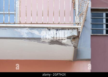 Un balcon avec béton fissuré et un fer rouillé nécessitant une rénovation. Banque D'Images