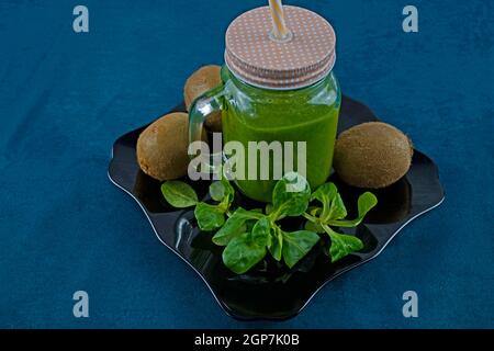 Smoothie aux feuilles de saladet au kiwi sur une assiette noire et décorée avec kiwi et laitue Banque D'Images