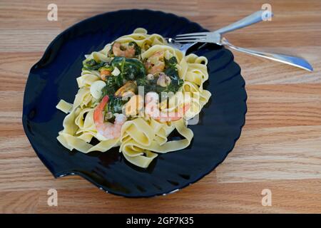 Fettuccine avec sauce à la crème au fromage aux épinards et fruits de mer une plaque Banque D'Images