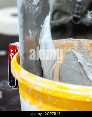 Seau d'enduit blanc mastic contre mur sur la reconstruction. Banque D'Images