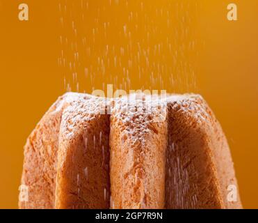 Avec Pandoro saupoudrage de sucre glace sur fond orange Banque D'Images