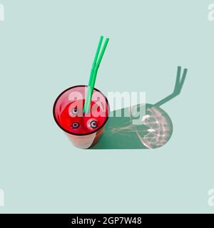 Un verre rempli de boisson rouge, avec des boules d'oeil dans le liquide et deux pailles vertes. Fond menthe pastel. Effrayant Halloween fête traditionnelle con Banque D'Images