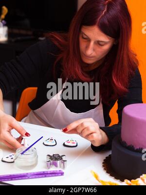 Leçon de pâtisserie, de travailler sur les chiffres de l'Halloween avec du fondant pâte ou pâte à sucre. Banque D'Images