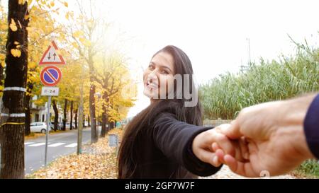 Une jeune femme court en tenant son petit ami par la main. Scène d'automne avec le geste de Follow Me qui raconte le concept de voyage en automne. Banque D'Images