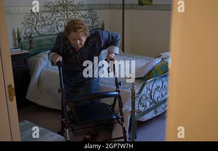 Une femme âgée sort du lit à l'aide de la marchette. C'est un outil très utile en présence de problèmes de moteur. Banque D'Images