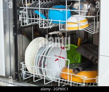 Vaisselle sale chargée dans un lave-vaisselle avec la porte avant ouverte. Banque D'Images