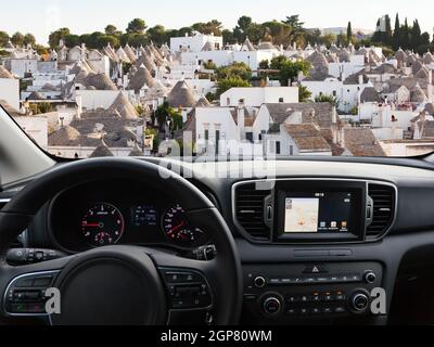 Vue d'un tableau de bord de voiture avec une unité de navigation voyageant à Alberobello Banque D'Images