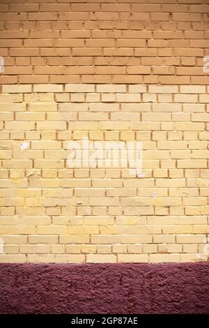 Mur de briques peint avec de la peinture jaune. La texture du mur du bâtiment. Surface peinte de la maison. Banque D'Images