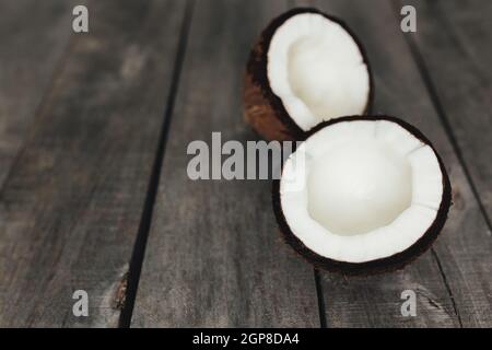 Noix de coco cassées sur fond en bois gris. Pâte de coco blanche. Photo de haute qualité Banque D'Images