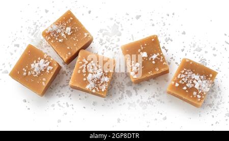 Vue de dessus des bonbons au caramel salé sur fond blanc avec des grains de sel comme garniture Banque D'Images