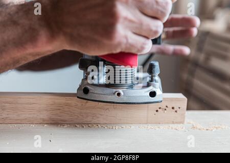 Gros plan la main mâle traite une planche en bois une jointer électrique, traitement de la pièce. Mise au point sélective Banque D'Images