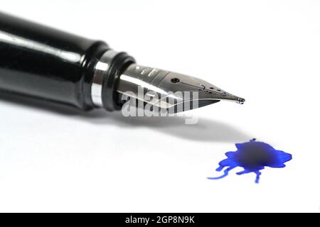 Gros plan d'un stylo plume classique avec une tache d'encre bleue sur fond blanc, espace de copie, mise au point sélectionnée et faible profondeur de champ Banque D'Images