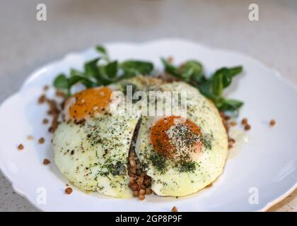 Œuf frit avec sarrasin et arugula sur une assiette blanche Banque D'Images