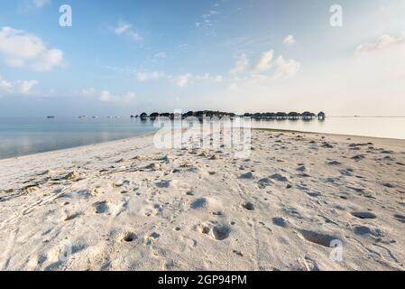 Bungalow sur l'eau des Maldives sur l'océan paysage d'eau. Crabes trous sur le sable de la plage au premier plan. Banque D'Images