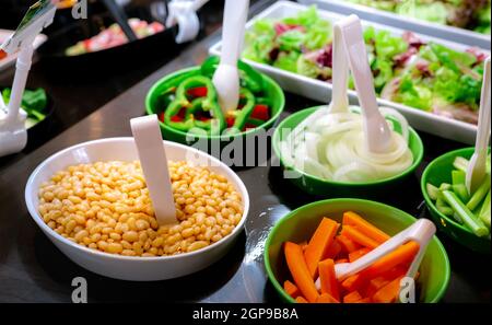 Buffet de salades au restaurant. Buffet de salades fraîches pour le déjeuner ou le dîner. Une alimentation saine. Haricots et carottes d'orange dans un bol blanc et vert sur le comptoir. Banque D'Images