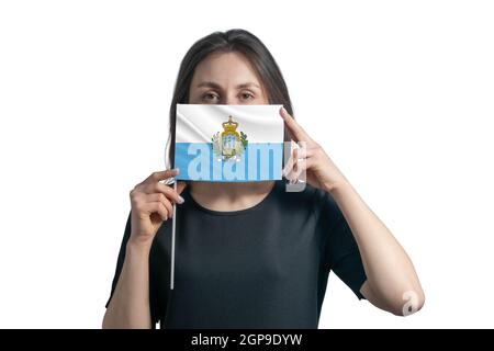 Bonne jeune femme blanche portant le drapeau de Saint-Marin et couvre son visage avec elle isolée sur un fond blanc. Banque D'Images