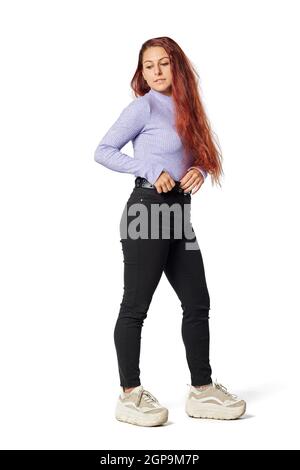 Une jeune femme de race blanche touche sa ceinture avec des cheveux longs et des vêtements décontractés. Banque D'Images