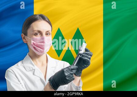 La jeune fille prépare la vaccination contre le fond du drapeau de Saint-Vincent-et-les Grenadines. Concept de vaccination Saint Vincent et le Grenad Banque D'Images